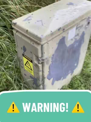 The cover image features an outdoor gray metal box covered in patches of lighter paint, positioned in tall green grass. A yellow warning sign with a lightning bolt is on the front.