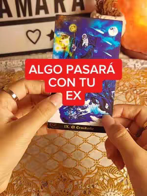 A person is holding a tarot card in their hands, with a red banner that says "ALGO PASARÁ CON TU EX" in Spanish. The background has a candle, a sign with a heart, and a decorative item. The image uses warm lighting.