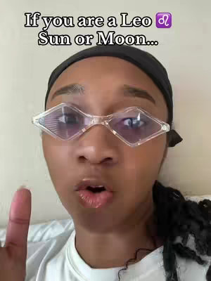 A close-up shot of a person with a dark headscarf. They are wearing clear, diamond-shaped glasses. The person has dark skin and is looking directly at the camera with their mouth slightly open. The text overlay reads, 'If you are a Leo ♌ Sun or Moon...'