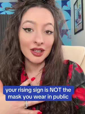 A woman with long, wavy brown hair is centered in the frame, looking directly at the camera. Her makeup includes bold eyeliner and red lipstick. She is wearing a floral red-and-black patterned top. The background includes a framed picture and hints of a blue patterned wall with curtains. A blue rectangular text overlay near the bottom contains the video's message.
