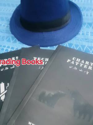 The cover image features a stack of three black books with titles in English and Urdu, a blue fedora hat at the top, all set against a light blue patterned background.