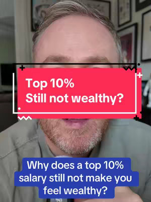 A close-up shot features a man with short, graying hair and a beard. He is centered within the frame. A red rectangular banner in the center of the image displays the text "Top 10% Still not wealthy?" in white, bold font. Below the red banner, a blue rectangular banner carries the text: "Why does a top 10% salary still not make you feel wealthy?" in white font. The background seems to be a domestic setting, with glimpses of framed artwork.