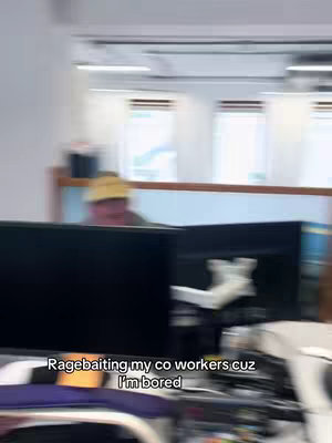 The cover image shows a blurred office environment with computer monitors in the foreground. A person wearing a yellow hat is visible in the background, partially obscured by office dividers. The overall composition is slightly out of focus, giving a sense of motion or quick capture.