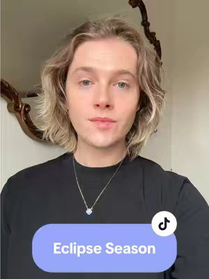 A selfie-style shot features a person with fair skin, light blond hair, and a black t-shirt. The person has a neutral expression and is looking directly at the camera. The background includes what appears to be a mirror and a white wall. A sticker with text \ Eclipse Season \ is added at the bottom of the screen.