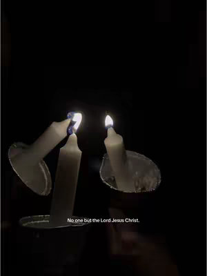 A dark image with three candles in the foreground. The candles are lit, and their reflections are visible on the surface below them. At the bottom of the image, there is overlaid text.