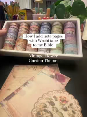 The image shows a tray filled with rolls of washi tape in various colors and patterns. In the foreground are two pages decorated with floral and vintage themes. The text overlays the image with the title and theme.