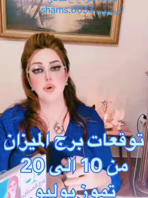 The image shows a woman in front of an ornate picture, with text overlays in Arabic script in the bottom half; she is looking toward the viewer, wearing glasses and a blue top, with styled hair and makeup. Behind her is an out-of-focus setting, suggesting a home environment.