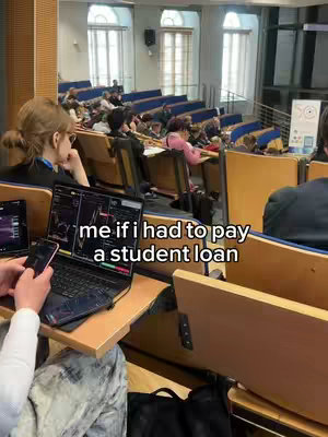 The cover image shows a person in a lecture hall setting, looking at a laptop displaying what appears to be financial trading graphs. Text overlaid on the image reads 'me if i had to pay a student loan'. The background shows a crowded lecture hall with several rows of seats filled with students.