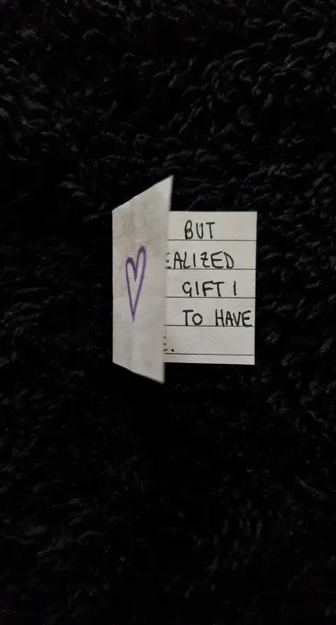 The cover image features a piece of folded, lined paper with a heart drawn in the top left corner. The right side of the paper is open, with handwritten text displayed in vertical lines. This is set against a black, textured background that appears to be a fuzzy fabric.