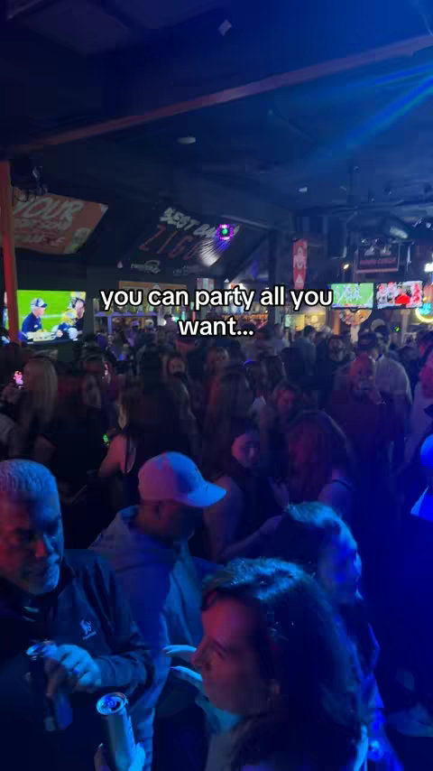 A crowded bar scene with many people visible, in low lighting. The image has a blue tint, contributing to the mood, with the hook text overlayed on the image.