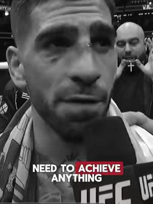 A black and white image featuring a close-up of a man, likely a fighter, mid-speech with a microphone. He has a serious expression, and the text overlay reads "NEED TO ACHIEVE ANYTHING". Background includes a man with a beard and a cross necklace.