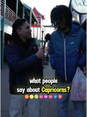 Two men are standing on a city street, with one holding a microphone, interviewing the other. Text overlaid on the image asks what people say about Capricorns.