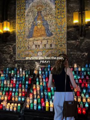 The cover image depicts a person, viewed from the back, standing in front of a wall of burning candles. Above, a religious painting or mosaic is mounted. The artwork features a central seated figure. The scene has a warm, inviting feel due to the candle lights.