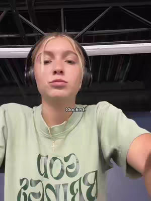A selfie-style image shows a young woman with blonde hair and headphones. She is wearing a light green shirt with the words "God Brings" visible. A small text overlay reads "Clocked."