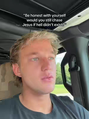 A selfie-style shot inside a vehicle, focusing on a young man with light-colored hair and light eyes. He is sitting in the driver's seat, and text is overlaid at the top, asking, "Be honest with yourself would you still chase Jesus if hell didn't exist?"