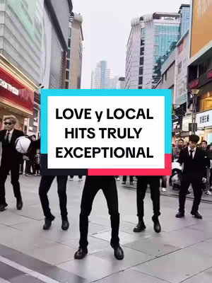 A photo of a group of men in black suits dancing in the middle of a city street. The background features a mix of modern buildings, with a sign that says 'LOVE y LOCAL' on the image.