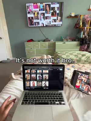 A person is lying in bed, a laptop is in front of them displaying images. A TV is above the bed displaying images as well.
