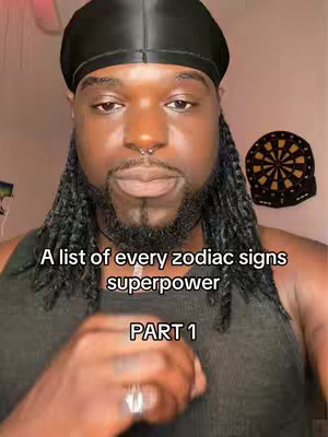 The cover image features a man with long dreadlocks, a black durag, and a piercing in his nose, centered in the frame. Text overlays read 'A list of every zodiac signs superpower' and 'PART 1'. A dartboard is visible in the background. The man wears a black tank top and a ring. The lighting is soft and appears natural.