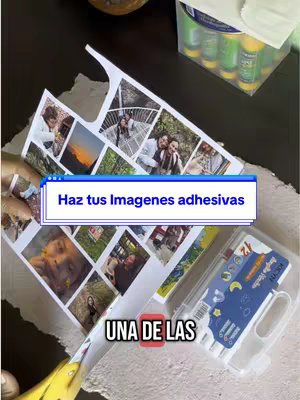 The image shows a table with a collage of printed photos and various crafting supplies. The focal point is a sheet of photos arranged in a grid, some cut around to look like stickers, with the text "Haz tus imagenes adhesivas" overlaid. A tray of adhesive sticks and other crafting supplies are visible.