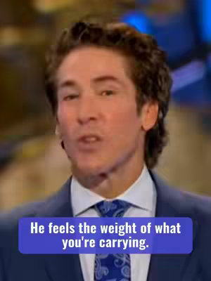 The image is a medium shot with a man in a suit as the main subject. The man, who appears to be Joel Osteen, is positioned from the chest up, with his head and torso dominating the frame. He has short brown hair and is looking slightly off to his right with a subtle expression. He wears a dark blue suit and a patterned tie. A purple banner with white text overlays the bottom of the image, which says, 'He feels the weight of what you're carrying.'. The overall composition is well-lit, with soft, diffused lighting that creates a professional appeal, using a background that is out of focus with muted blue and grey tones.