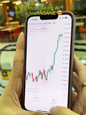 A person holding a smartphone displaying a stock chart on the screen. The phone is angled towards the camera, with the background out of focus, suggesting the photo was taken indoors.