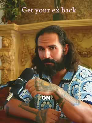 A man with long dark hair reaching his shoulders, a full dark beard, and tattoos on his arm is in the video. A microphone is positioned on the left. The setting has golden-colored decorative walls and a backdrop with plants, suggesting a studio or a well-decorated room. Text overlays read 'Get your ex back' and 'ON'.