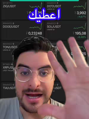 A selfie-style shot featuring a man in glasses, positioned center-frame, against a dark background displaying cryptocurrency trading data. The man has a hand raised towards the camera, covering part of the screen. A text overlay in Arabic scripts reads "اعطيك". The overall composition is a mix of financial data display and personal expression.