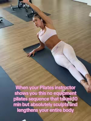 A woman in athletic wear performs a side plank on a blue exercise mat. The background includes wooden flooring, workout equipment, and a glimpse of a fitness studio setting. Text overlays are pink and white, showcasing workout benefits.