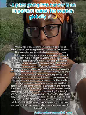 A woman with short hair , wearing glasses, headphones, and an orange headscarf, is centered in a selfie-style shot. Overlayed text discusses Jupiter's transit through Cancer for women, and its impact. The background suggests an outdoor setting, but the focus is primarily on the woman's face and the text overlay.