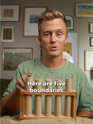 A man in a green shirt stands in front of a wall with framed pictures. He is holding a stand with five glass tubes. The text overlay reads, "Here are five boundaries."