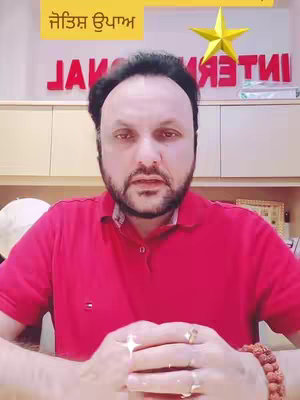 A man with a beard and red collared shirt sits in front of a camera. The background includes a decorative star and text in a foreign script with a yellow banner on top.