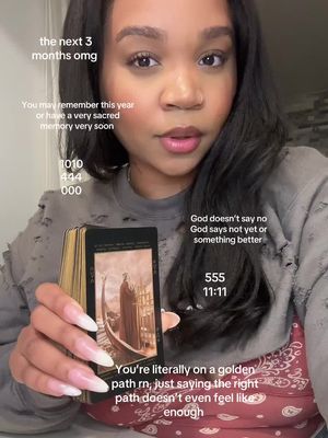 The cover image shows a woman holding a deck of tarot cards and looking directly at the camera. Text overlays are scattered across the image, including phrases related to a golden path and spiritual messages, and numbers, and various texts. She is wearing a gray sweater with ripped details, with long nails, and her hair is long too.