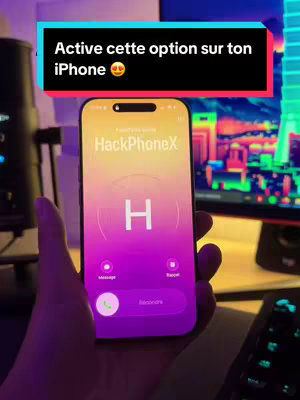 The cover image shows a person holding a phone with an app displaying a call screen with a large letter 'H'. Above the phone, a text overlay reads: 'Active cette option sur ton iPhone 🤩'. The background shows a dark desk setup with a computer and accessories.