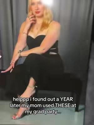 A woman in a black jumpsuit and heels is seated, seemingly in a photo studio, with a soft, blurred neutral background. Bright light reflects off her skin. The text overlay at the image’s bottom is a caption.