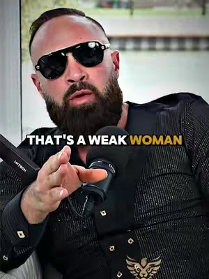 A man with a beard and sunglasses is holding a microphone in front of a light brown background with the text overlay "THAT'S A WEAK WOMAN".