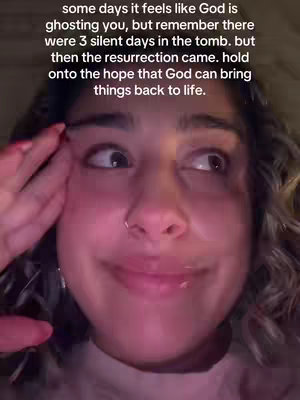 A close-up shot features a woman with light skin, dark hair, and a nose ring. She's looking off to the side with a thoughtful or emotional expression, her hand raised near her face. Overlaid on her image is white text conveying a message of faith and hope. The overall composition suggests a video that speaks to religious beliefs, the lighting appears to be warm.