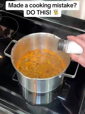 A close-up of a pot on a stovetop with soup inside. A hand is pouring salt from a salt shaker into the soup. Above the pot, white text on a black background states, 'Made a cooking mistake? DO THIS!'