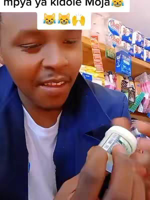 A man is holding a roll of something resembling tape or a sticker container. The man is looking upwards with a slight smile, while an overlay of text, emojis and a hand gesture are included above the man.