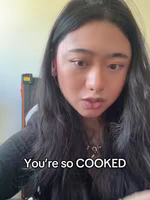 A young woman with long, dark hair is positioned in front of a light-colored background. The text overlay 'You're so COOKED' is placed at the bottom of the frame. The woman is looking towards the camera.