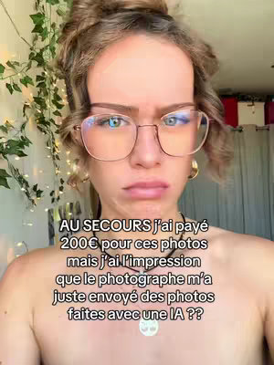 A young woman with a skeptical expression looks directly at the camera. She wears glasses with round frames and large hoops. Her hair is up and out of her face. The background shows hints of a room with fairy lights and curtains. The text overlay on the image expresses frustration about photos possibly made by AI.