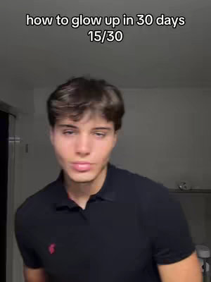 A young man with light skin and brown hair stands in front of a neutral background. He is wearing a black collared shirt with a small red logo on the chest. Text overlays at the top of the image read "how to glow up in 30 days" and "15/30".