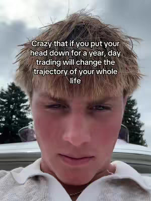 A close-up shot of a young man's face against a blurry background. The man has light skin, short, messy blonde hair, and appears to be looking down with a thoughtful expression. Overlaid on top is a white text box containing a motivational quote related to day trading.