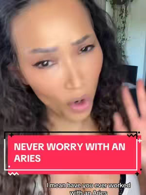 A woman with dark hair and light skin is looking up slightly with her mouth open. A red banner with white text overlays the bottom third of the image that contains the text "NEVER WORRY WITH AN ARIES". The backdrop is blurred and seemingly indoors.