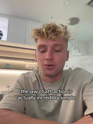 A young man with light-colored hair and a light green t-shirt is centered in the frame, speaking directly to the camera. The background is a bright, clean space with white walls and a light oak-colored shelf. A text overlay appears at the bottom, conveying a message.