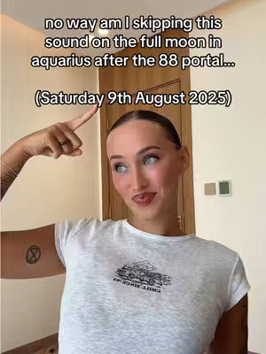 A woman with fair skin and light blue eyes is pointing upwards with her right index finger. The text overlay reads, "no way am I skipping this sound on the full moon in aquarius after the 88 portal...(Saturday 9th August 2025)." She wears a white t-shirt, and in the background, there is a room with beige walls and a wooden door .