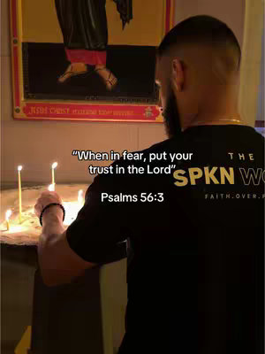 A man with a beard and black t-shirt lighting candles in front of what appears to be a religious painting, with text overlaying the image.