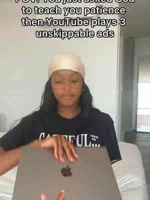 A woman holding a laptop, with overlayed text on a light background. The woman is the focus, holding the laptop towards the camera. The text overlay expresses a humorous observation about the experience of waiting for unskippable ads on YouTube when seeking patience.