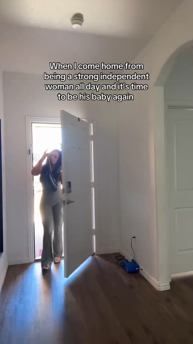 A woman in casual attire stands in a doorway, hand raised, as if preparing to enter. The scene is set in a home interior with a wooden floor, a bright hallway, and white walls. Text overlays the image.