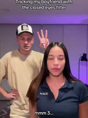 The cover image features two people: a woman in a blue polo shirt and a man wearing a cap and a tan shirt. The woman is the primary focus and appears to be talking. The hook text at the top reads, 'Tricking my boyfriend with the closed eyes filter.'