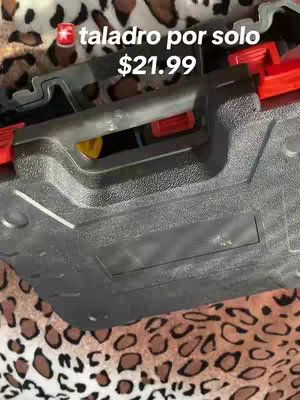 The image shows a partially open black and gray toolbox. The background is a leopard print pattern. Text overlay in Spanish says 'taladro por solo $21.99' with a small red star icon.